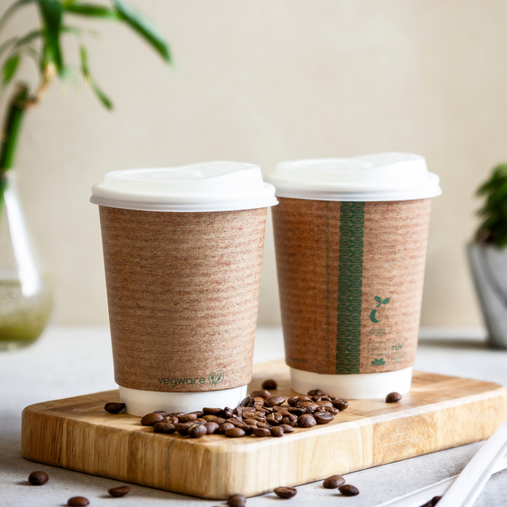 Two Vegware double wall cups on a wooden board with coffee beans