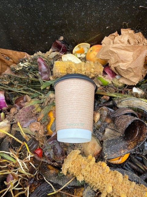 A Vegware cup and lid in a hot composter